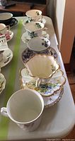 Five china teacups stacked inside matching saucers, floral patterns, gold trim visible