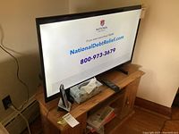 Hisense 40" TV displaying NationalDebtRelief.com advertisement on wooden cabinet, remote control and tissue box beside TV