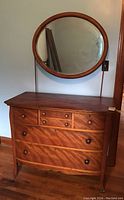 Full view of the vintage wooden dresser and attached round mirror, showing overall appearance and condition.