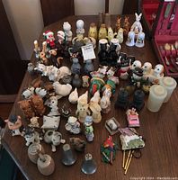 Wide view of entire collection of vintage ceramic and novelty salt and pepper shakers arranged on wooden table.
