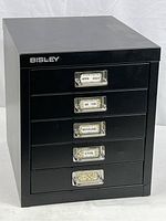 Front view of black 5-drawer Bisley cabinet with labels on drawer fronts.