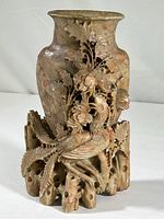 Front view showing the overall shape, marbled color, and intricate carved bird and floral design on soapstone vase.