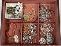 Overhead photo of the jewelry lot showing divided tray with various earrings and necklaces