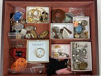 Top-down photo of assorted costume jewelry in box compartments, including hoops, large earrings, and charms.