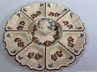 Top-down view of ceramic serving tray showing all 9 compartments with floral decoration and scalloped edges.