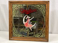 Front view of the square Miller High Life beer bar mirror with wooden frame showing woman on crescent moon logo and decorative gold corners.