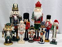 Front view of all nine wooden nutcracker figures showing their varied designs and sizes from 6 to 15 inches.