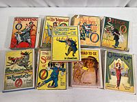 Nine Wizard of Oz books with illustrated dust jackets arranged in two rows on white background