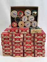Top-down view of a box with small wooden spools of Coats & Clark sewing thread, plus the boxed thread spools stacked underneath showing original red and cream labeled boxes.