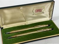 Pen and mechanical pencil set displayed in original green velvet-lined box with cream satin interior lid bearing Cross logo.