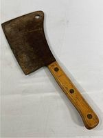 Full view of vintage meat cleaver with metal blade and wooden handle.