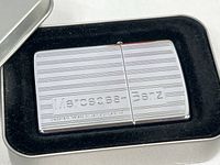 Close-up of the chrome lighter showing Mercedes-Benz logo and linear design.