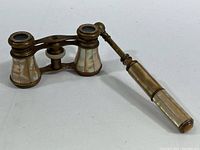Full view of the opera glasses with decorative attached handle, showing mother-of-pearl inlays and brass frame.