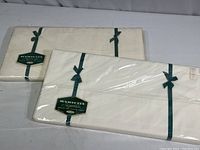 Two sealed packages of vintage Wamsutta Supercale full size flat sheets laid out side by side, tied with green ribbon.