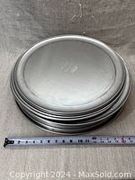 Stacked round aluminum pizza pans showing smooth flat bases and ridged edges for baking pizzas.