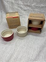 Photo showing two sets of baking ramekins in their original Vintage Kitchen boxes by Typhoon, each box containing two ramekins with one cream and one red visible.