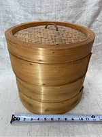 Full height stack showing three layers and woven lid with handle, measuring tape indicating 12 inches wide.