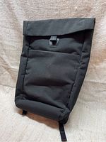 Image showing front exterior of black Bellroy backpack with top flap and leather strap snap button closure.