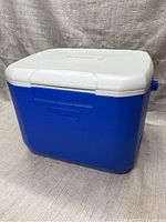 Closed view of the blue and white Coleman cooler with the Coleman logo on front.