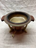 Full image of the fondue/chafing dish showing copper bowl with wooden handles and brass frame with fuel holder beneath