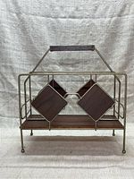 Front view of the metal and wood Mid-Century Modern record rack, showing the diamond-shaped wooden accents and wooden base platform held within a gold-tone metal frame.