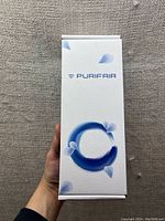 Closed white box with Purifair branding and blue circular graphic design on front.