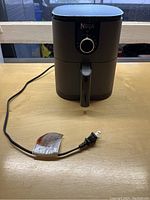 Front view of the Ninja air fryer with power cord visible on table.