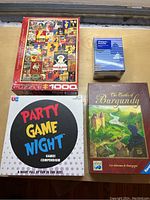 Four puzzle and board game boxes: 1000-piece collage puzzle, Party Game Night, small Planners Puzzle box, The Castles of Burgundy