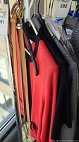 Designer jackets hanging on black and white hangers near a window, colors coral/red, black, and grey visible.