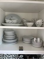 Shelved china set including stacked plates, tea cups with saucers, gravy boat, and salt & pepper shakers.
