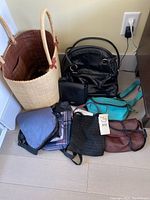 Photo of multiple handbags and shoulder bags including straw tote, black handbag, turquoise bag, and others