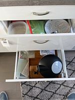 Opened drawers showing various kitchen utensils including strainers, bowls, kitchen scale, and storage containers