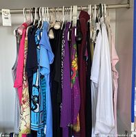 Wide view of assorted ladies clothing on hangers, showing variety of tops, sweaters, and blouses in medium and large sizes.