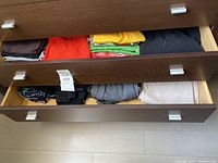 Two drawers with folded women's sport clothing items including shorts, shirts, and jackets in various colors and sizes medium and large.