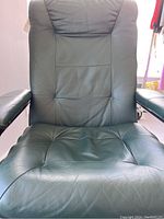 Front view close-up of green leather padded seat and backrest on the recliner chair.