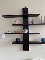 Full view of wall-mounted dark wood shelf with various stone and ceramic figurines arranged on shelves.