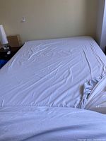 Full view of the queen size bed with mattress and fitted sheet, showing the bed frame against a wall