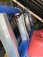 Side view of two ladders chained together inside a storage or vehicle space, showing metallic frame and blue Featherlite ladder.
