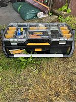 Closed DeWalt tool caddy showing brand logo and handle on grass outdoors