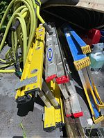 Yellow Featherlite aluminum extension ladder and multiple additional aluminum extension ladders stacked together