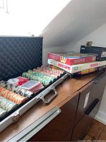 Metal carry case open showing poker chips stacked in orderly rows with two decks of playing cards inside.