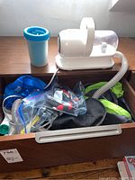 Drawer containing Neakasa pet dryer with hose, attachments, and dog grooming items.
