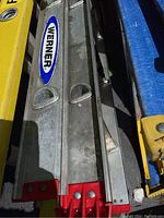 Close-up photo of aluminum Werner ladder side rails with red feet and Werner brand label.