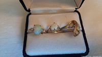 Three ladies rings with opals set in gold bands displayed in a jewelry box.
