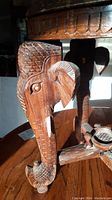 Side view showing carved elephant head leg with detailed ears, eye, trunk, and tusks.