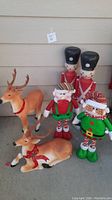 Full group showing 2 plastic soldiers, 2 plastic reindeer, and 2 fabric elves, displayed on a concrete surface.
