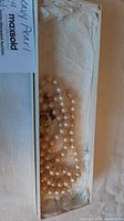 Pearl necklace and earrings set inside original box, showing full strand and clasp.