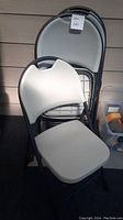 Single plastic and metal folding chair with beige/gray seat and backrest, folded and upright chair shown