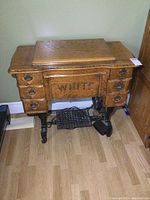 Frontal view of antique White sewing cabinet showing the wood top, six drawers with metal handles, and the 'WHITE' brand name on front panel.
