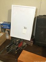 Craftsman belt sander with attached power cord, plastic storage case behind it, and several boxes around the items on a table.